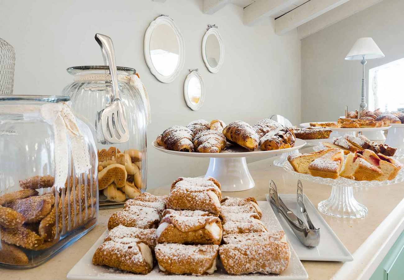 Buffet di dolci con croissant, cannoli e biscotti in un ambiente luminoso.