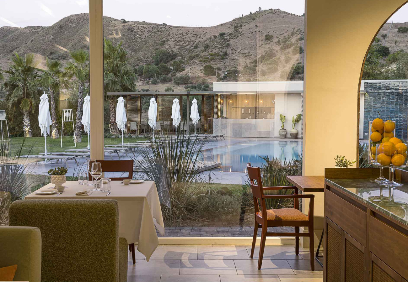 Ristorante elegante con vista su piscina e colline, atmosfera rilassante e raffinata.