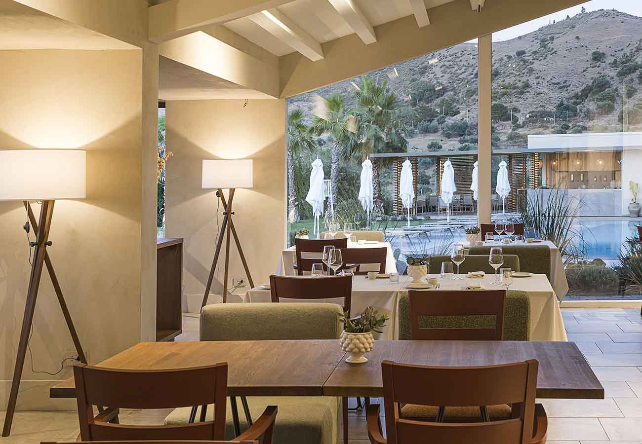 Ristorante elegante con vista su colline, arredi moderni e ampie vetrate.