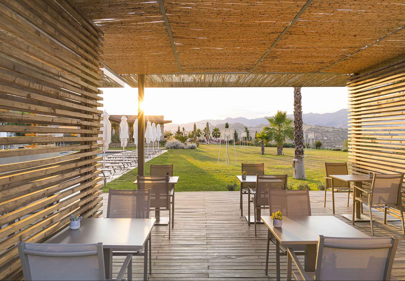 Terrazza con tavoli all'aperto, vista montagna, al tramonto.