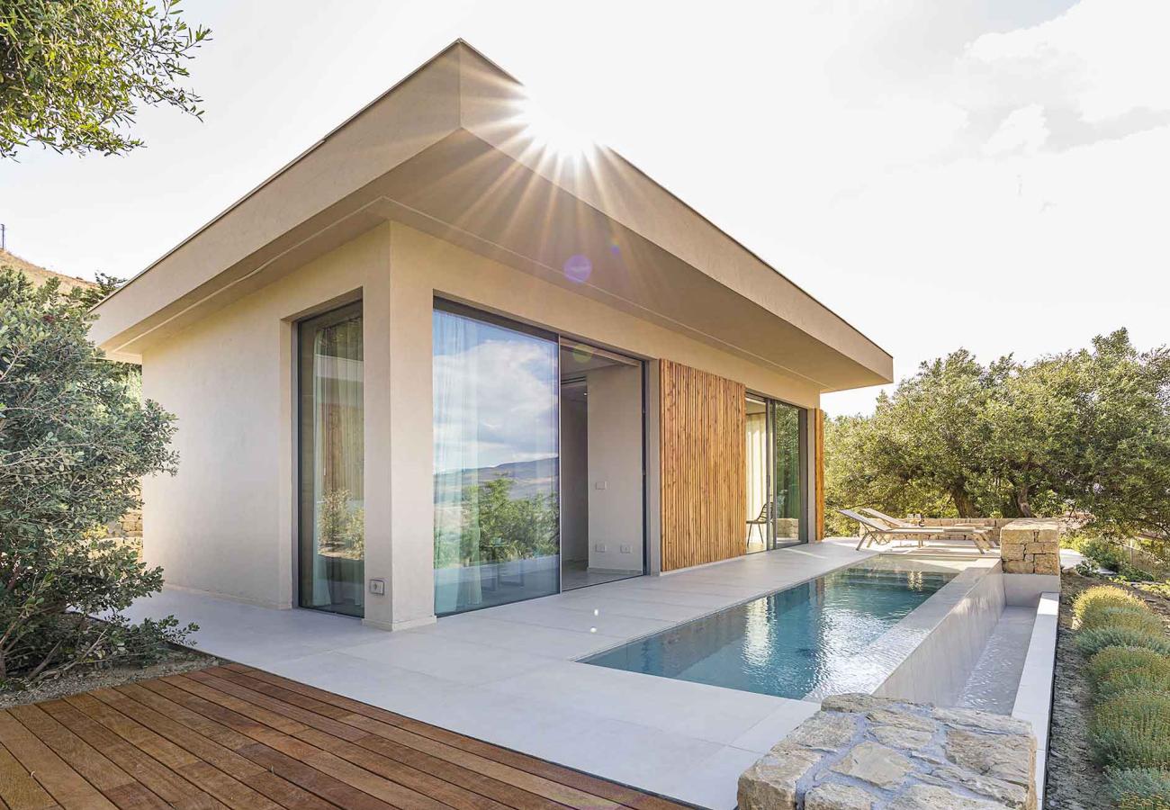 Moderna villa con piscina, ampie vetrate e terrazza immersa nel verde.